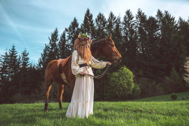 Crystal Visions I Photograph by Mako Miyamoto. Wookie in a white dress and flowers in her hair leading a horse through a magical field